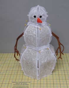 Photo of assembled freestanding embroidered snowman with pins holding sections in place