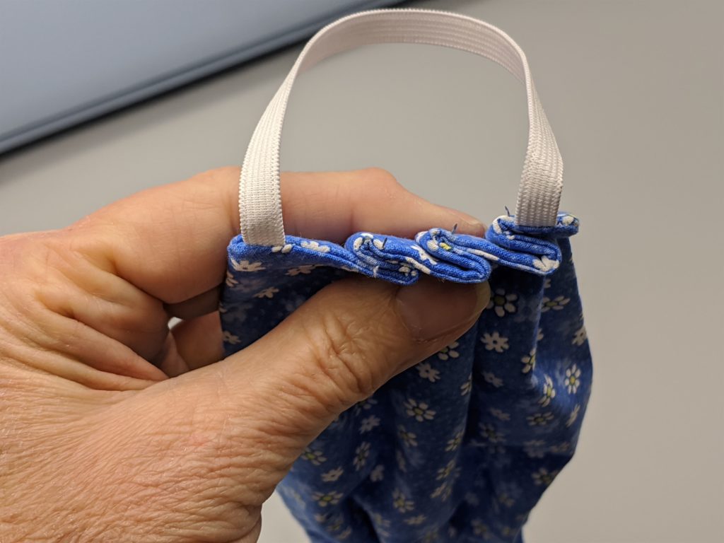 Side view of face mask showing how folds should line up beside each other and not overlap.