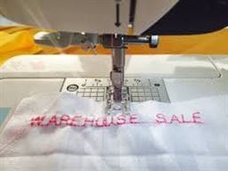 What's the Buzz: May Events at Rocky Mountain Sewing and Vacuum 1 photo of Warehouse Sale embroidered on a piece of white fabric.