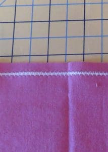 How to Gather Fabric and Create Ruffles 8 Photo showing pink fabric with white dental floss encased in zig zag stitch to create a gather
