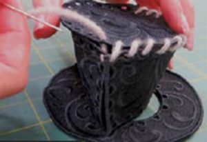 Photo of using yarn to sew the top of the hat to the sides for freestanding embroidered snowman