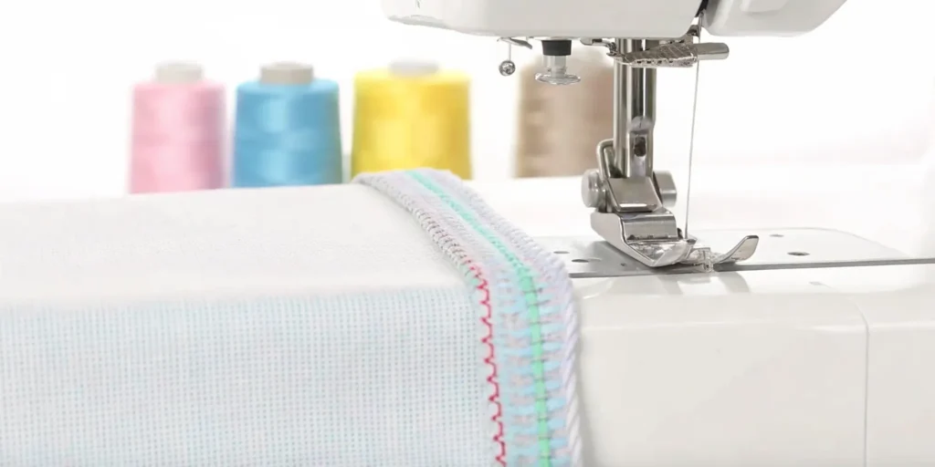 A close-up of a modern overlock sewing machine stitching colorful thread on a fabric edge with neat, professional overlock seams and bright spool cones in the background